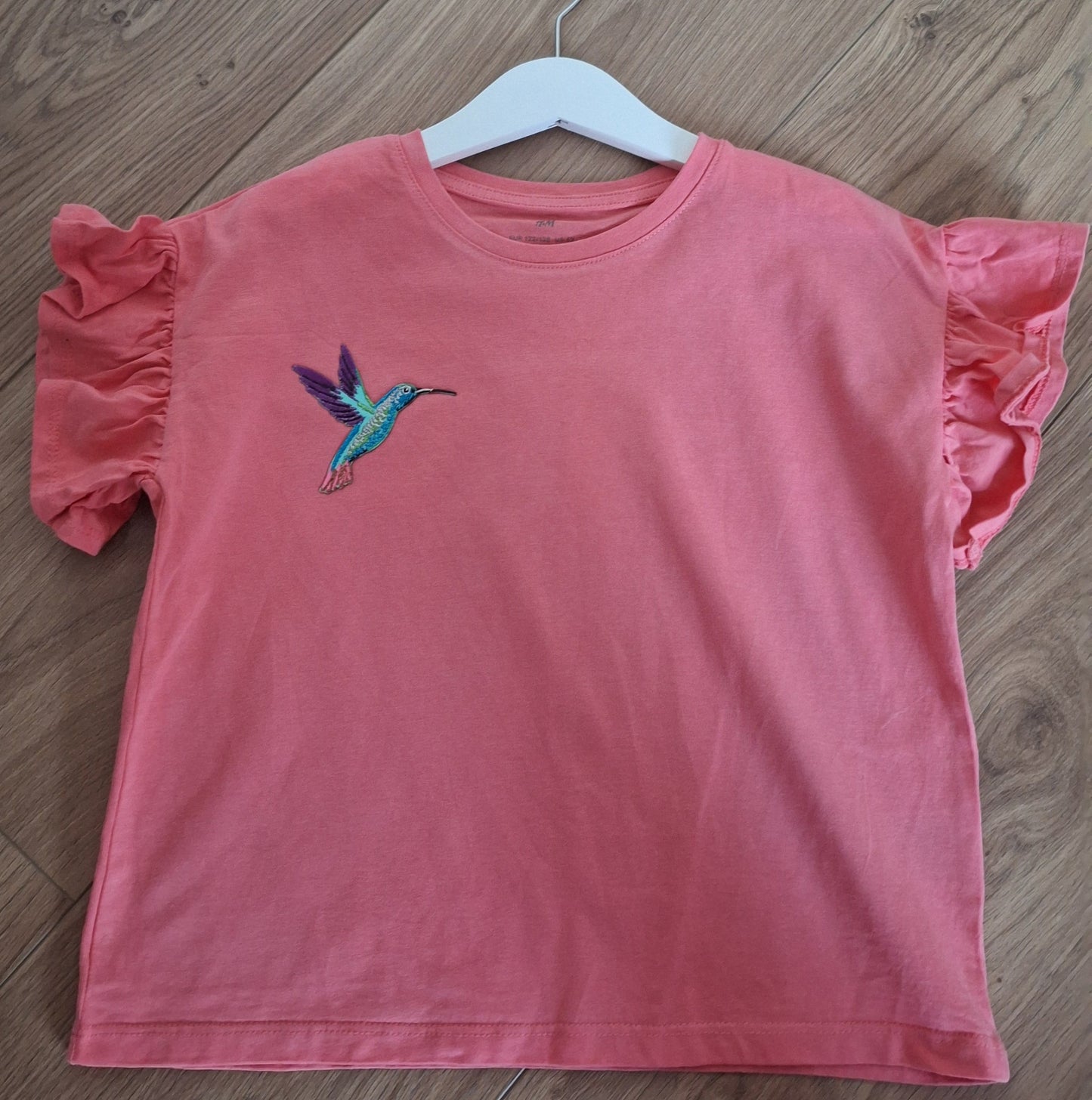 Kolibri embleem op shirt gestreken